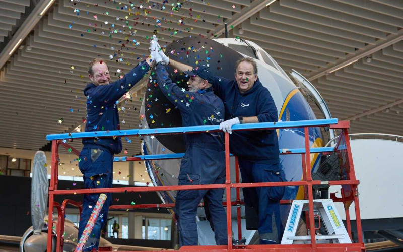 Drei Techniker stehen auf einer angehobenen Plattform vor der Nase der Lockheed \